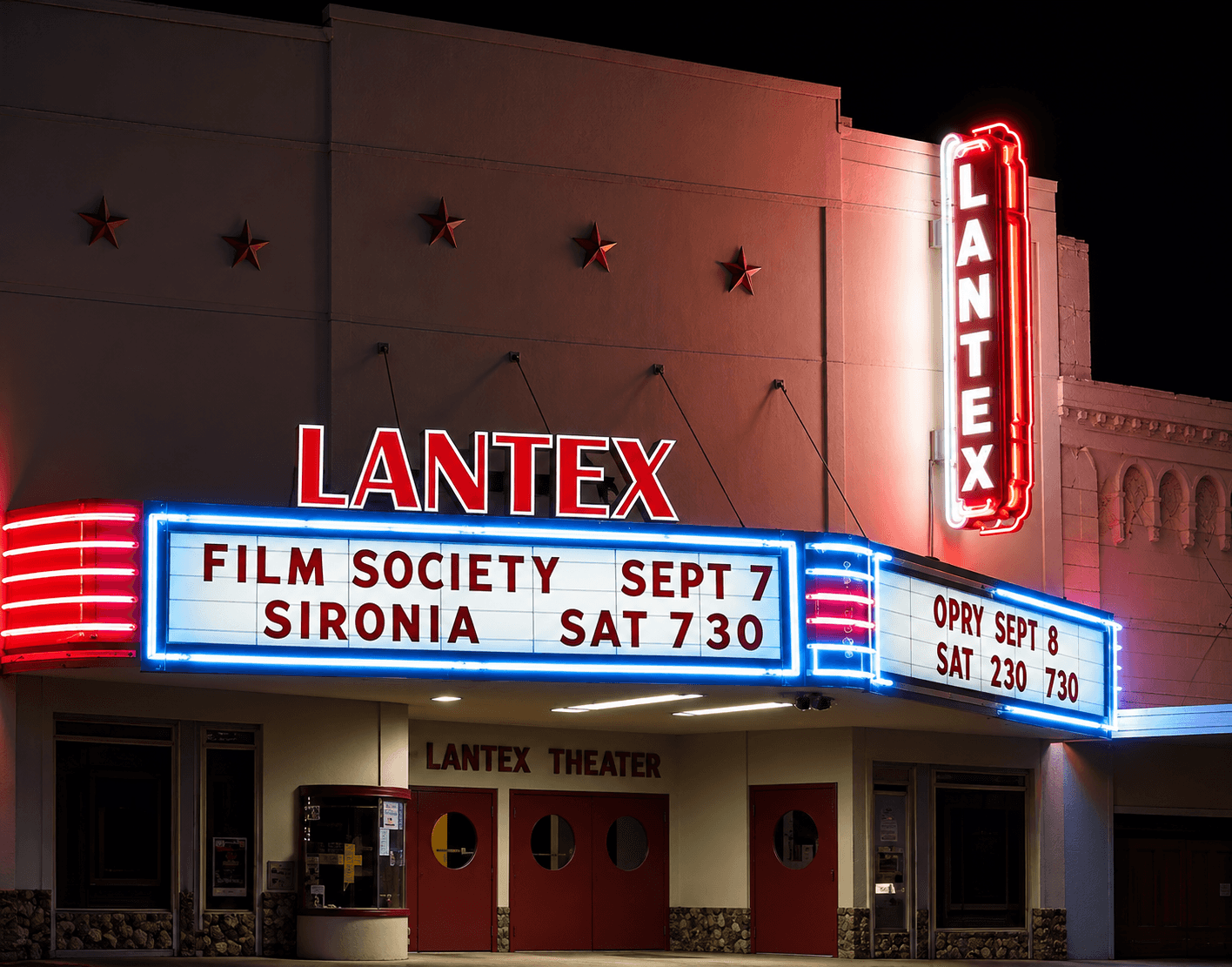The LanTex marquee lit in red and blue neon at night, Film Society and Opry on the boards